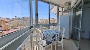 A balcony with a table and chairs, a refrigerator, and a view of a cityscape. - Ref: 227 Beach front apartment with pool and sea views in Torreblanca (Fuengirola)