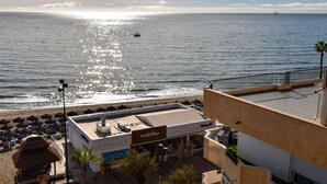 Un hotel frente a la playa con bar en la azotea, sombrillas y vista al océano.