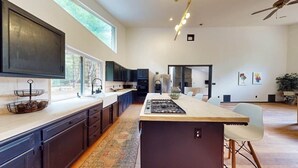 Een moderne keuken met donkere kastjes, een centraal eiland en een groot raam voor natuurlijk licht.