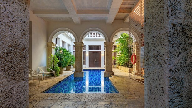 An indoor swimming pool with stone walls, arches, and potted plants. - Wynwood Casa Santisimo in Cartagena (Cartagena)