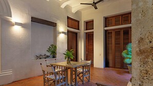 A dining area with a wooden table and chairs, a ceiling fan, and a potted plant. - Wynwood Casa Santisimo in Cartagena (Cartagena)