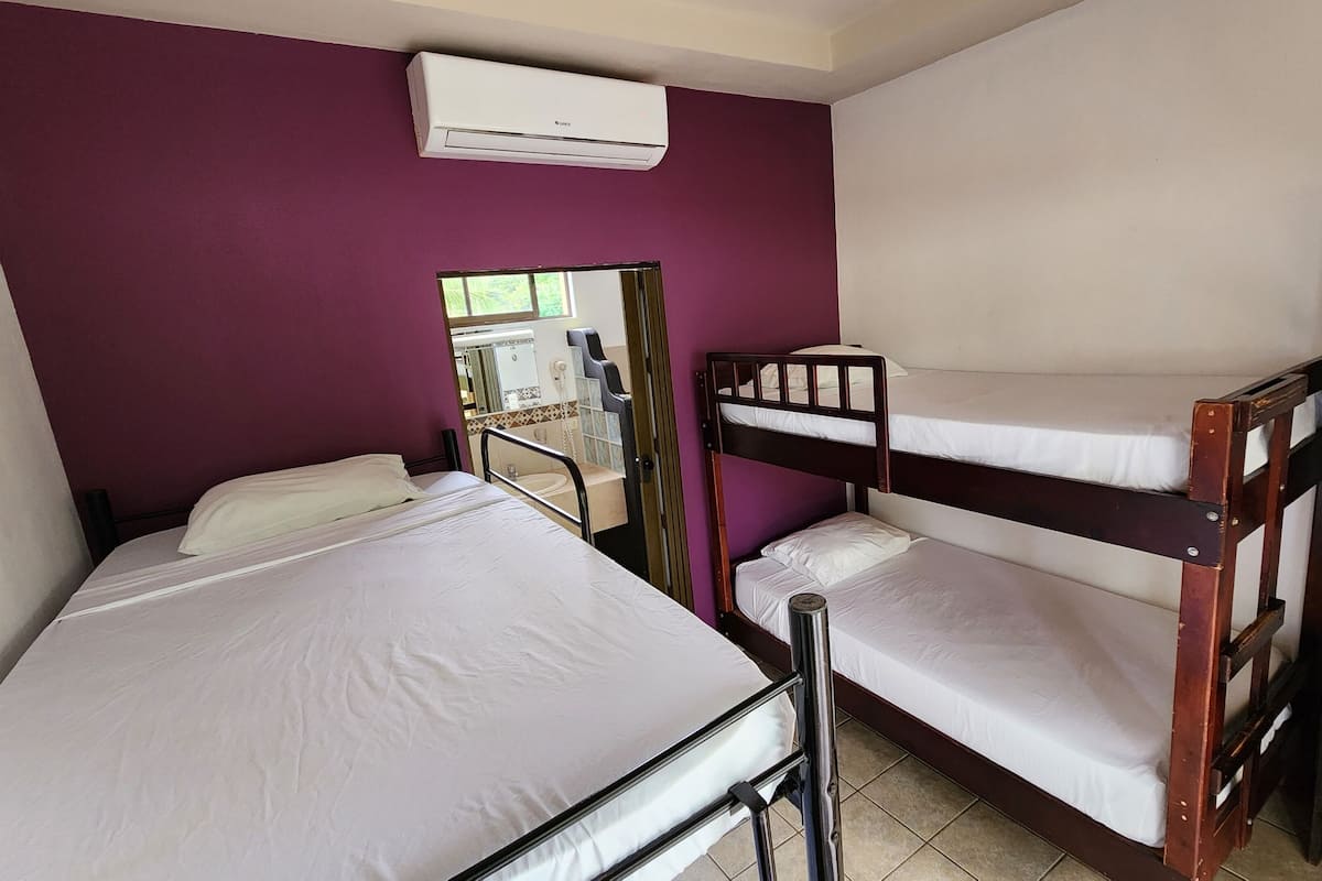 A room with two bunk beds, a window, and an air conditioning unit.