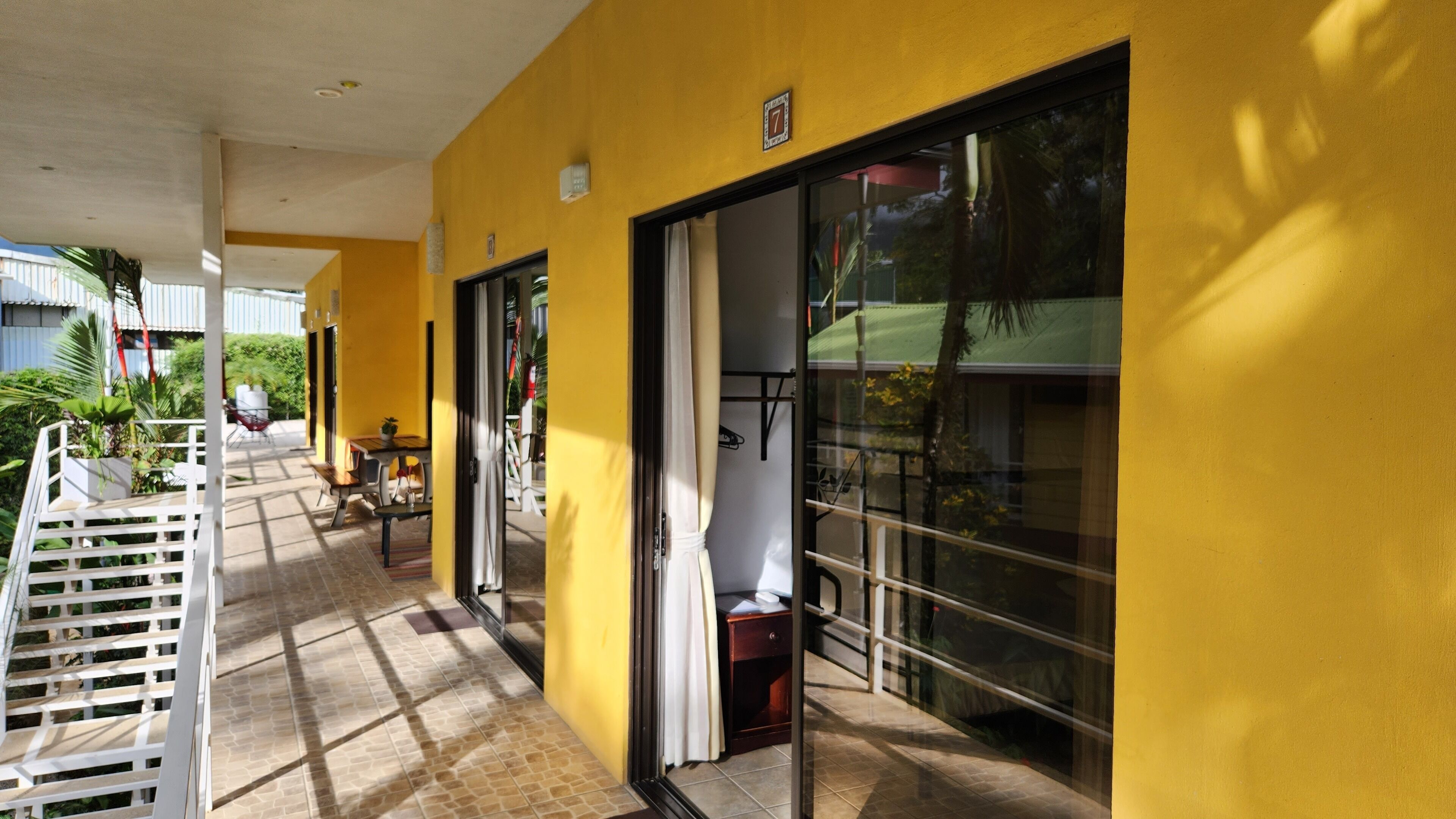 A corridor with a yellow wall, a door with a number plate, and a window with a metal frame.