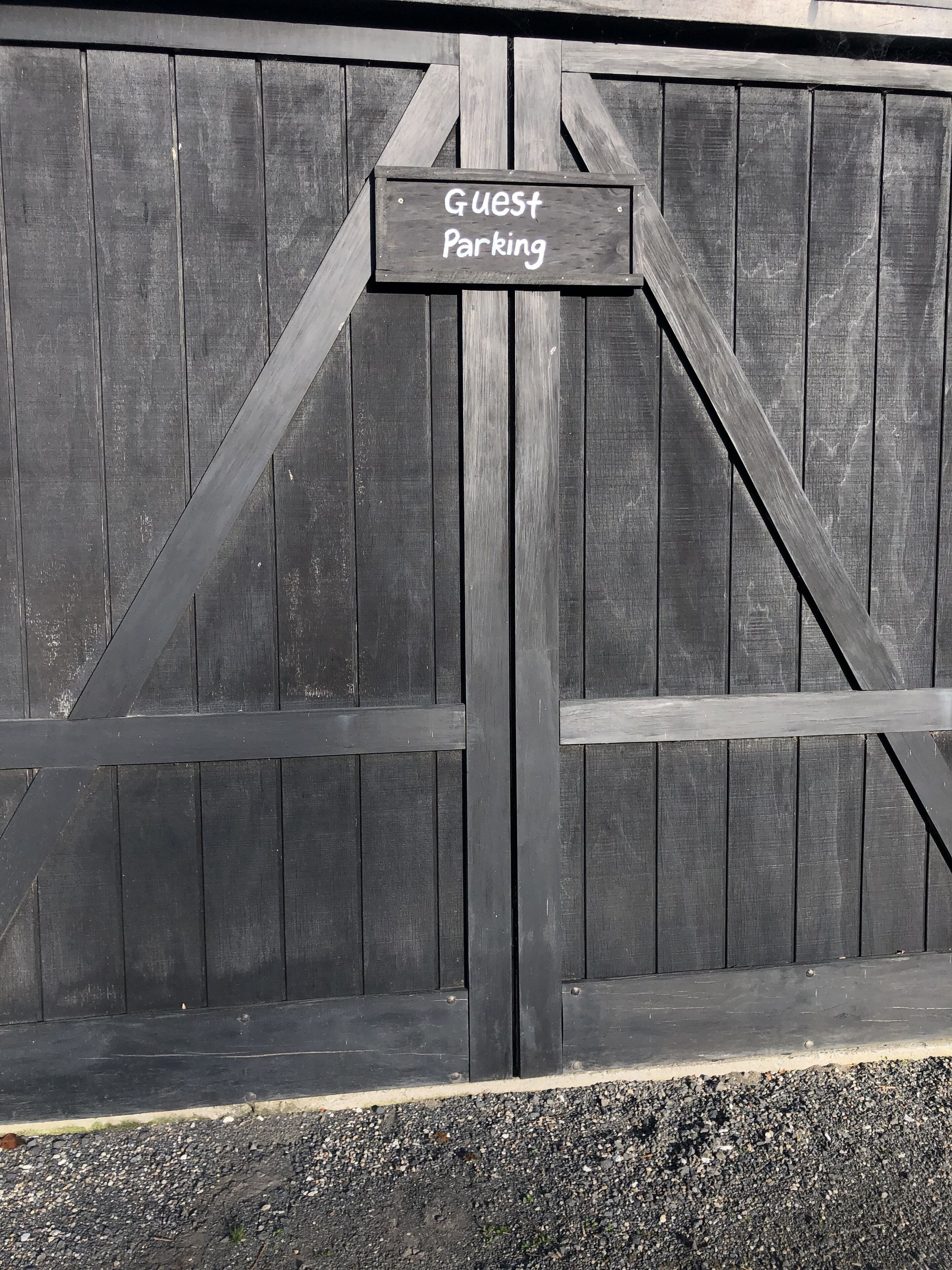 A wooden gate with a sign that reads "Guest Parking".