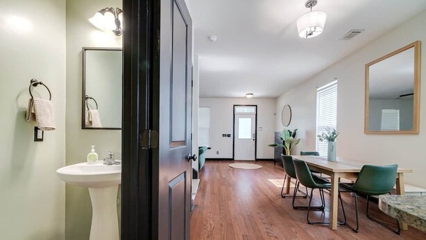 Une cuisine moderne avec un plancher en bois, un évier et un coin repas comprenant des chaises et une table.