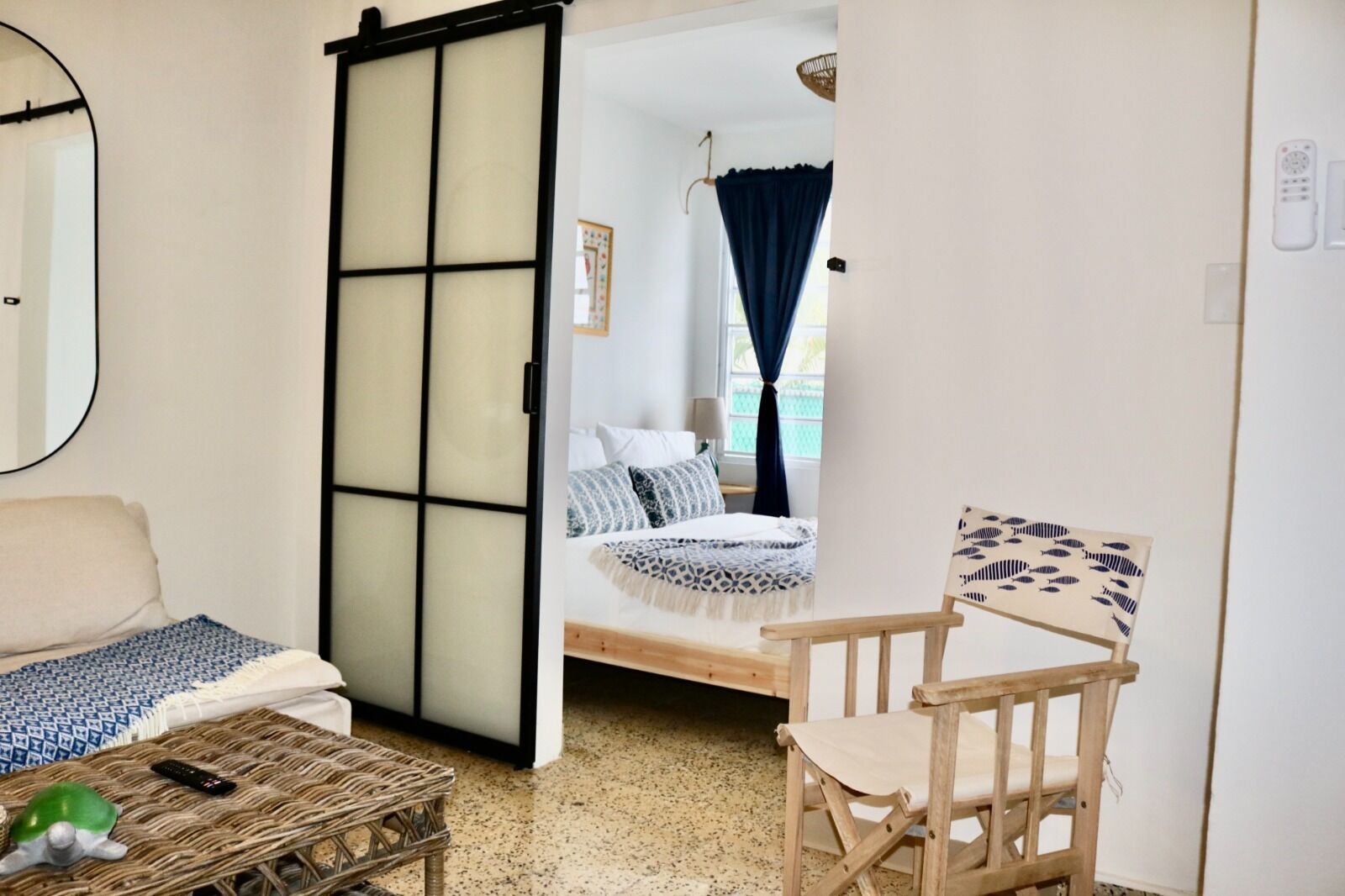 Een kamer met een bed, een stoel, een kleine tafel en een schuifdeur naar een andere kamer.