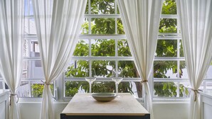 A room with a table, two chairs, a bowl, and a window with curtains. - Luxury 1 bed Apartment 9. Steps from the beach! (San Juan)