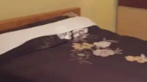 Een kamer met een bed, houten vloer en een wandlamp.