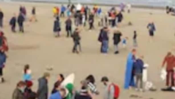 Een druk strand met mensen en tenten.