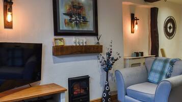 A living room with a television, a fireplace, a sofa, and a decorative shelf.