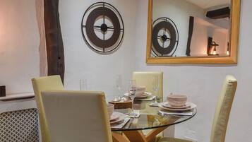 A dining area with a round table, chairs, and a large mirror above.