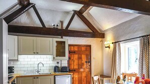 A kitchen with white cabinets, a wooden door, and a dining area with a table and chairs. - 3 bedroom accommodation in Church Stretton (Church Stretton)