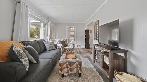 Una sala moderna con sofá, reposapiés y mueble para televisión.