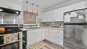Una cocina moderna con armarios blancos, electrodomésticos de acero inoxidable y una alfombra estampada.