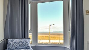 A bedroom with a bed, a window with a view of a beach and mountains, and a street lamp outside. - A beautiful two bedroom apartment with stunning views over Morecambe Bay. (Morecambe)