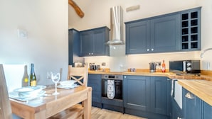 Una cocina moderna con armarios azules, una mesa de comedor de madera y un horno empotrado.