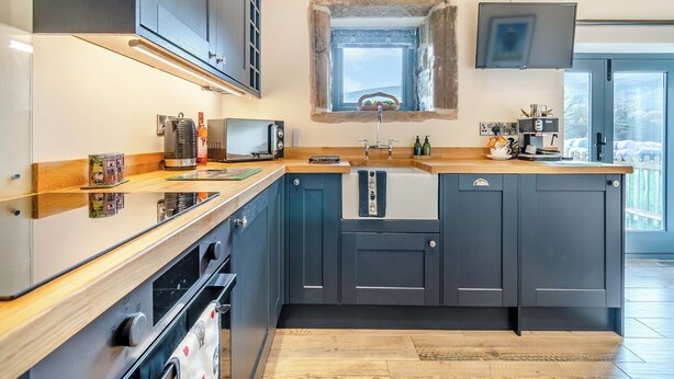 Una cocina moderna con armarios oscuros, un microondas, un lavabo y un ventanal sobre el lavabo.
