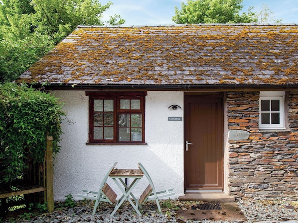A rustic cottage with a stone wall, a wooden door, and a window.