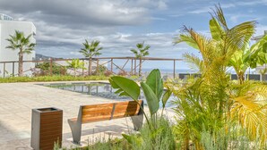 A rooftop pool area with a wooden bench, palm trees, and a view of the ocean. - Becas Place, a Home in Madeira (Funchal)