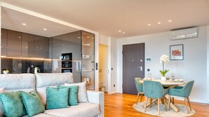 A modern living room with a sofa, a dining table with chairs, and a kitchen area with cabinets and appliances. - Becas Place, a Home in Madeira (Funchal)