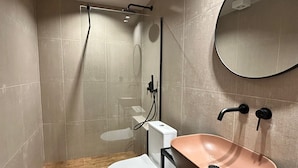 Et moderne badeværelse med bruser, toilet og vask.