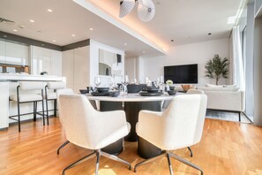 Un espace repas moderne avec une table ronde, des chaises blanches et un décor minimaliste.