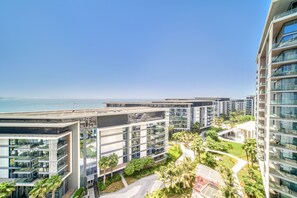 Un immeuble moderne de grande hauteur, doté de nombreux balcons, d’une terrasse sur le toit et offrant une vue sur l’océan.