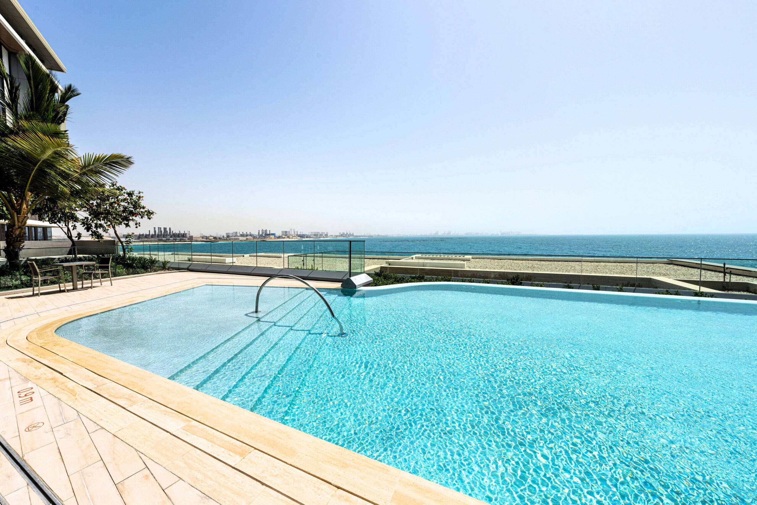Ein Pool mit Blick auf das Meer und eine Stadtkulisse im Hintergrund.