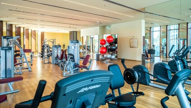 Ein Fitnessstudio mit verschiedenen Trainingsgeräten, darunter Laufbänder und Kraftgeräte.