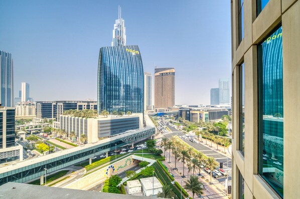A modern cityscape with a prominent skyscraper, a wide road, and surrounding buildings.
