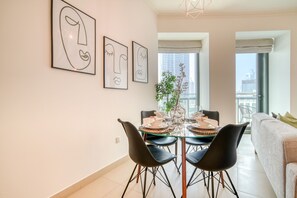 A modern dining area with a glass table, black chairs, and minimalist decor.