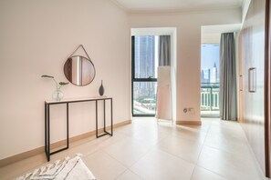 A modern hotel room with a large window offering a city view, a console table with decorative items, and a minimalist design.