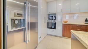 Eine moderne Küche mit Edelstahlgeräten, weißen Schränken und einer Arbeitsplatte aus Granit.