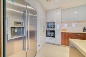 A modern kitchen with stainless steel appliances, white cabinetry, and a granite countertop.