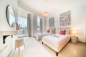 A modern hotel room with two beds, a large window with a city view, a round table, and a small side table with a lamp.