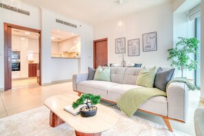 A modern living room with a sofa, a coffee table with a bonsai tree, and a dining area with a table and chairs.