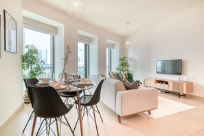 Moderni olohuone, jossa on sohva, ruokapöytä, tuoleja ja televisio.
