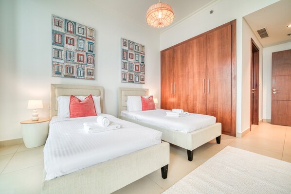 A hotel room with two beds, a wooden wardrobe, and artwork on the walls.
