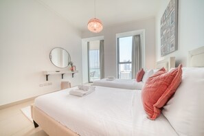 A modern hotel room with a large bed, a smaller bed, a bedside table, a mirror, and a view of the city.