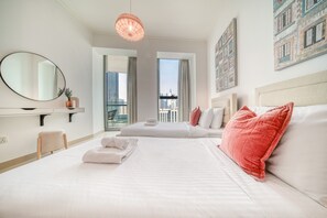 A hotel room with two beds, a large mirror, a city view, and a red pendant light.