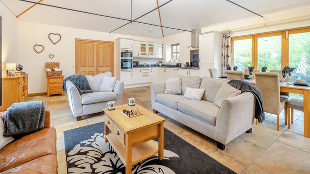 Een ruime woonkamer met een bank, een salontafel en een eettafel gedekt voor twee personen.