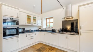 Een moderne keuken met witte kasten, een inbouwoven, een gasfornuis en een raam dat voor natuurlijk licht zorgt.
