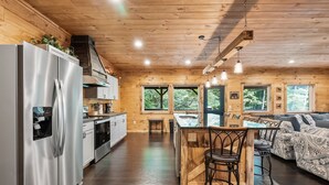 A modern kitchen with stainless steel appliances, wooden walls, and a central island with bar stools. - Lazy Bear Lodge by Inn & Spa at Cedar Falls (Creola)