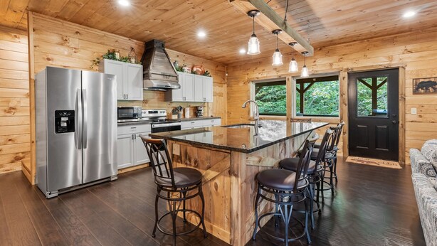 A wooden cabin interior with a kitchen, bar area, and seating. - Lazy Bear Lodge by Inn & Spa at Cedar Falls (Creola)
