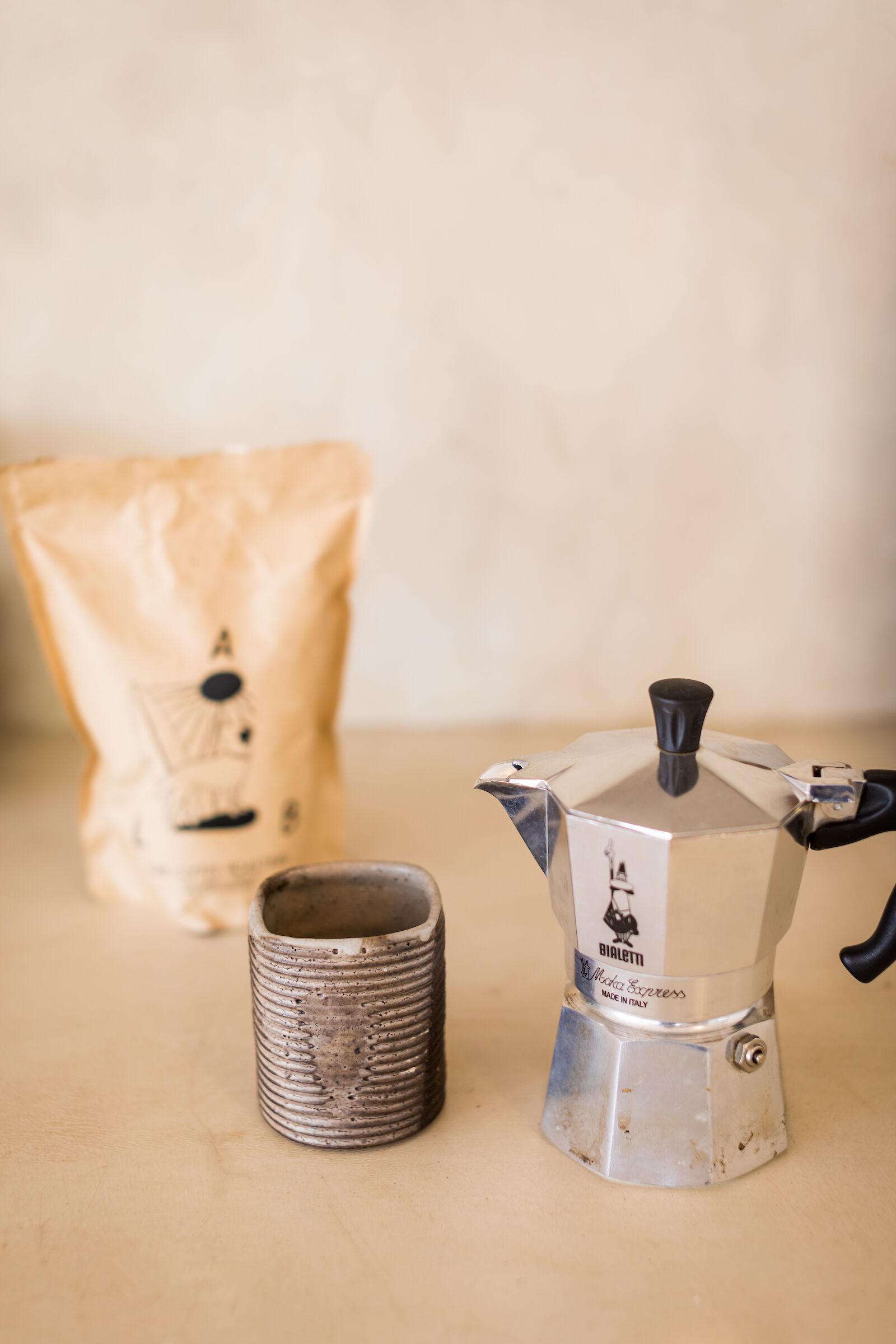 A coffee maker and a bag of coffee on a table.