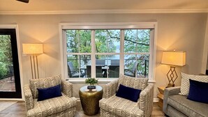 Un salon comprenant deux fauteuils à motifs, un canapé et deux poufs en cuir. Une table basse ronde, sur laquelle est posée une plante, se trouve au centre de la pièce.