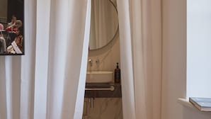 A bedroom with a bed, a mirror, and a bathroom visible through curtains. - The Townhouse (Udine)