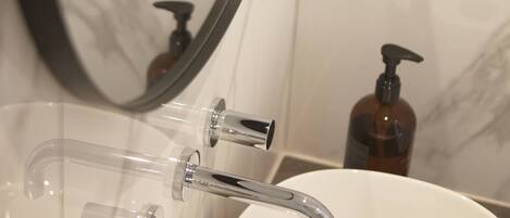 A bathroom with a white sink, a mirror, and a soap dispenser.