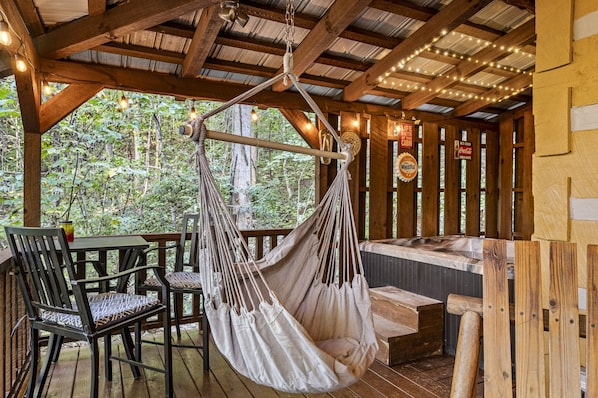 Une terrasse en bois avec un hamac, des chaises et un jacuzzi.