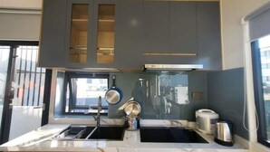 A modern kitchen with grey cabinets, a stainless steel range hood, a double sink, and a window providing natural light. - Apartment 2 double bed, modern, new, Nha Trang (Nha Trang)